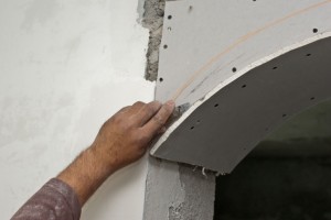 Cutting the excess drywall arch with a razor knife